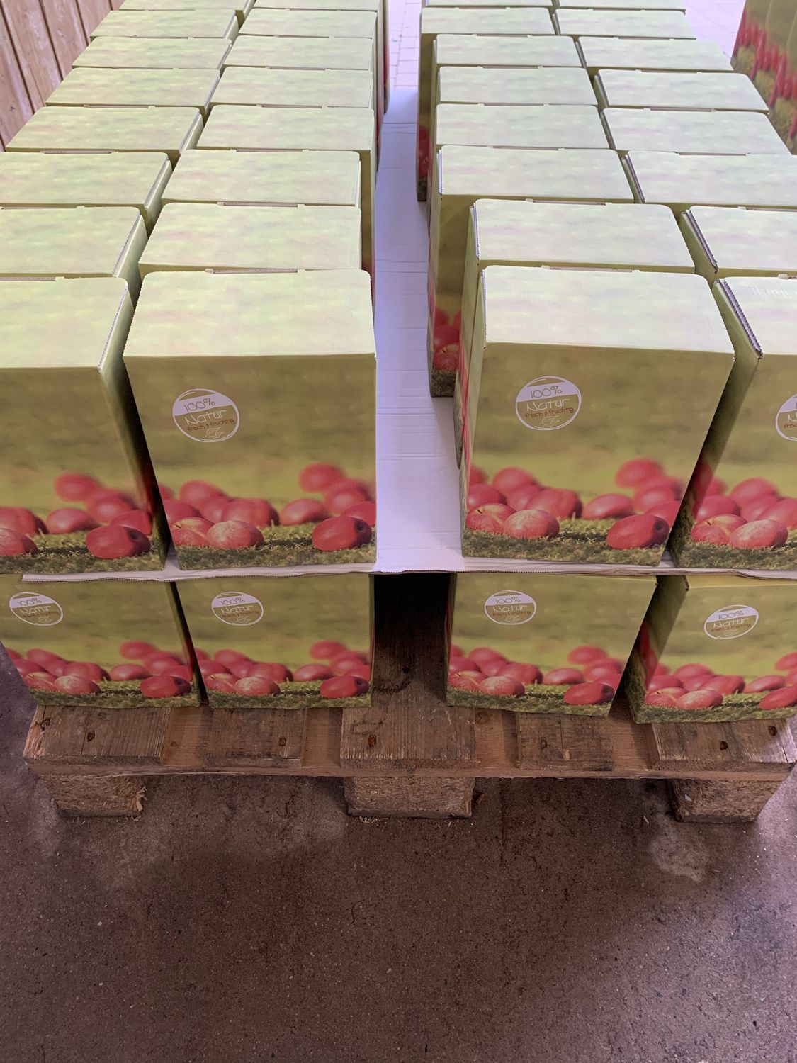 Gestapelte Bag-in-Box-Kartons mit Apfelmotiv auf einer Palette